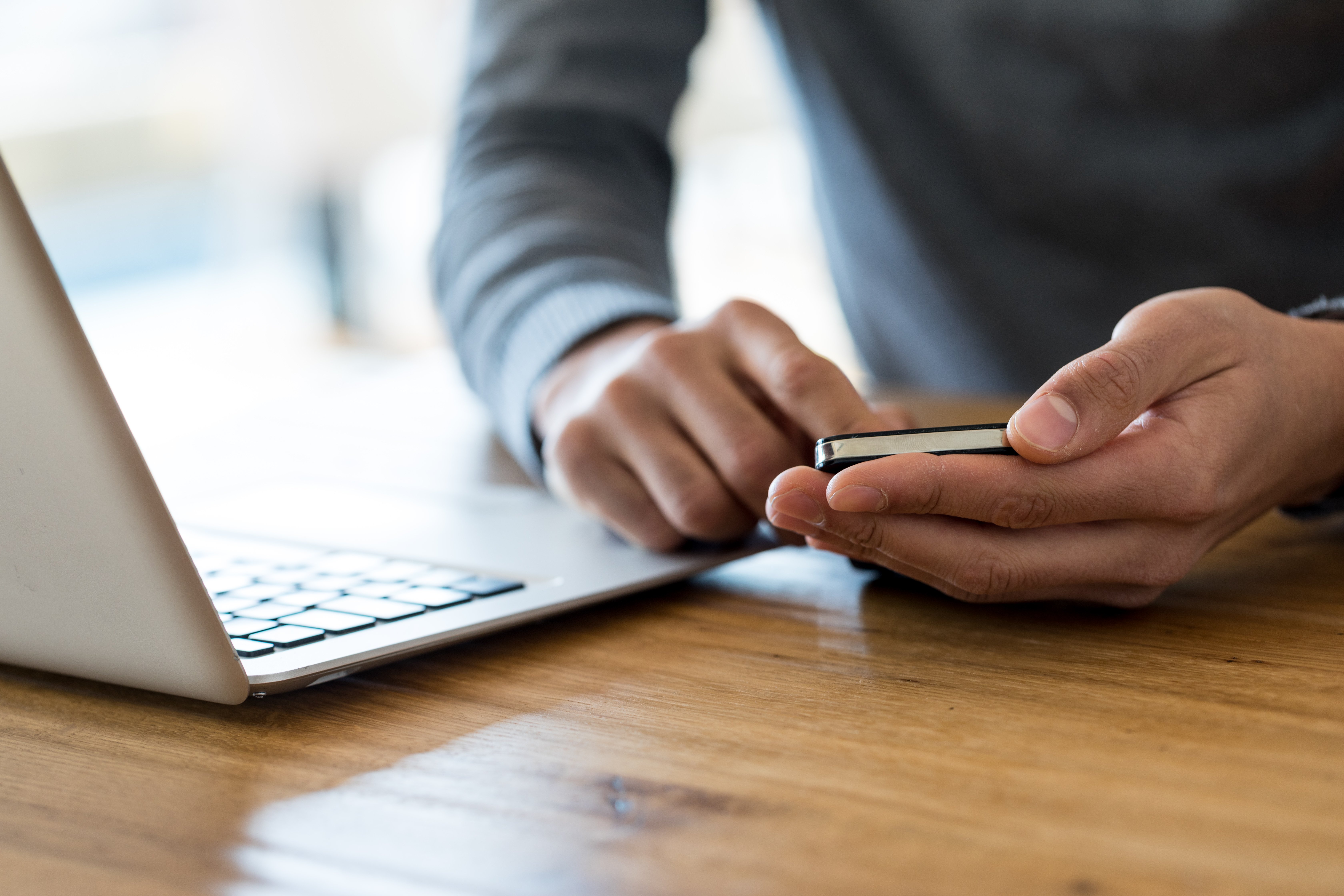 Cropped-of-man-holding-cell-phone-at-working-place-666135210_6720x4480 (1)