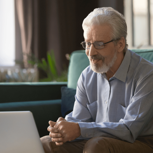 Elderly-man-sitting-on-couch-looking-at-computer