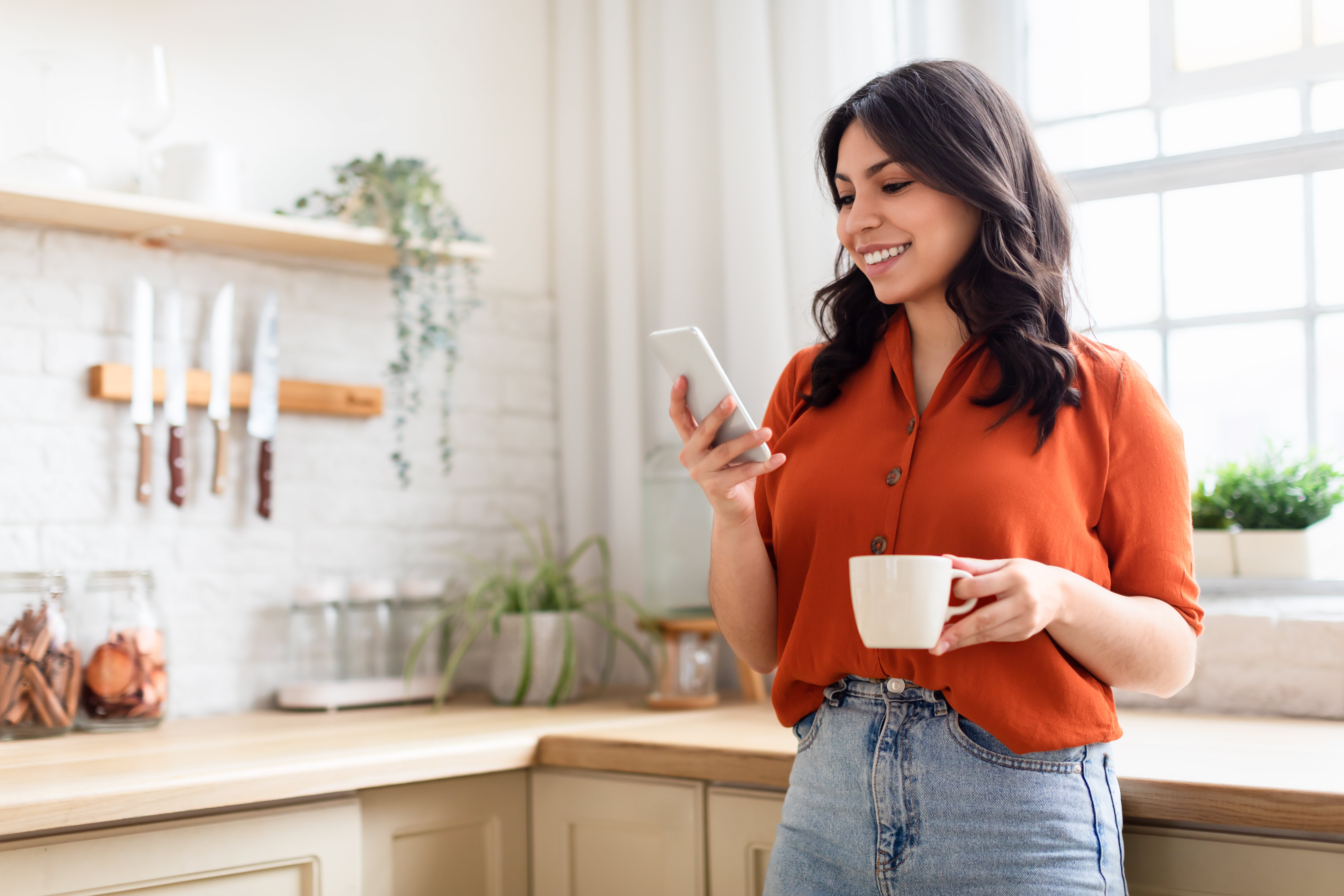 female-latin-american-adult-indoor-enjoying-her-coffee-while-using-her-smartphone-print