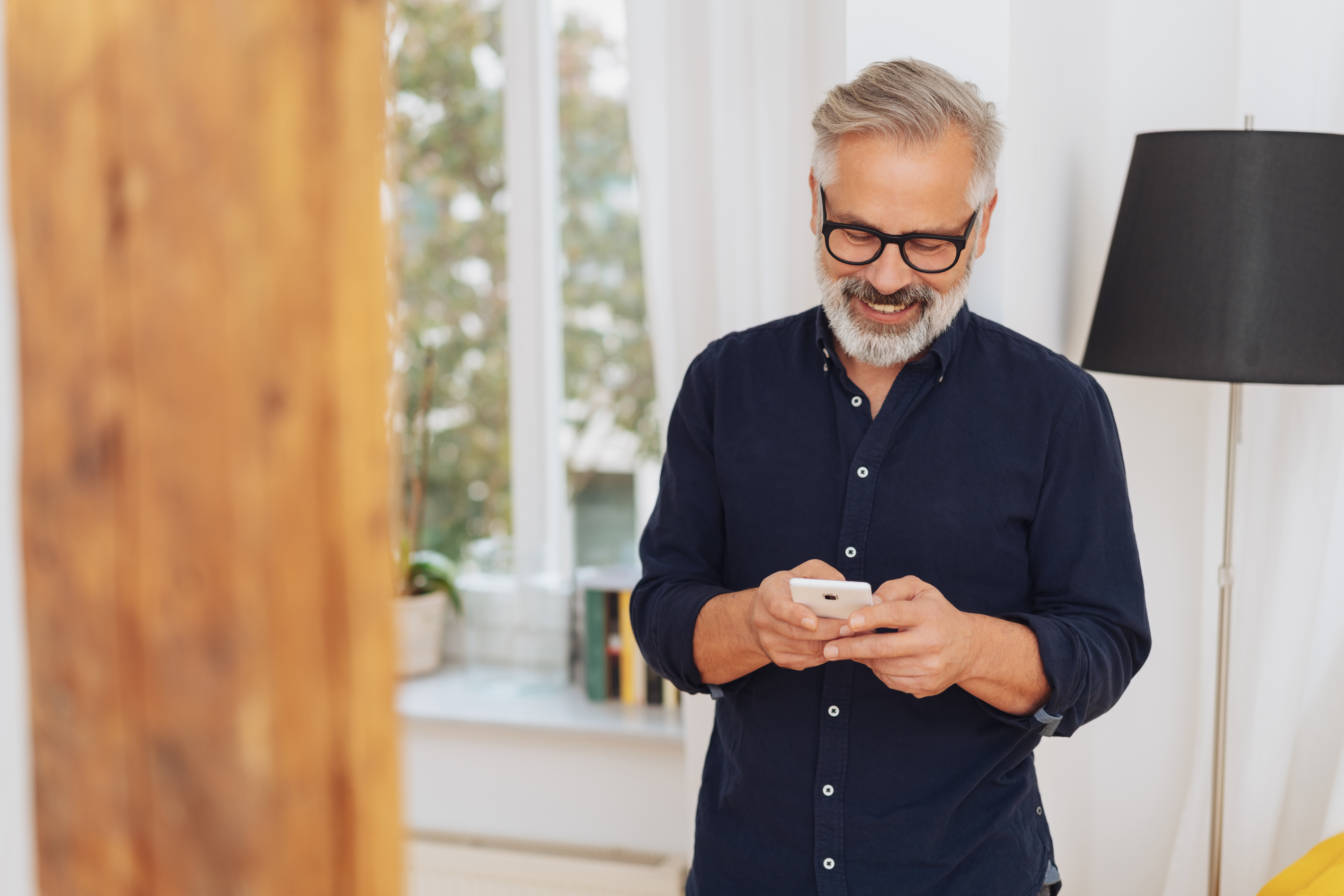 Attractive-man-smiling-as-he-sends-a-text-message-1073255992_7952x5304 (2)-1